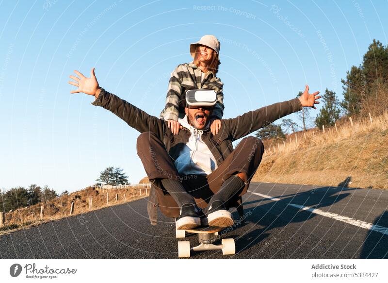 Glücklicher Mann und Frau mit Skateboard haben Spaß auf der Straße Paar Freizeit Virtuelle Realität Zusammensein Zeit verbringen Skater Aktivität Schutzbrille