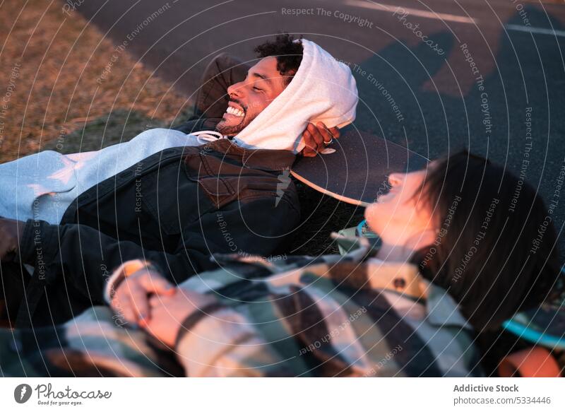 Positiv gestimmter junger Mann und Frau mit Skateboards im Gras liegend Paar Lachen Lügen Natur sich[Akk] entspannen Liebe Glück Partnerschaft Zusammensein