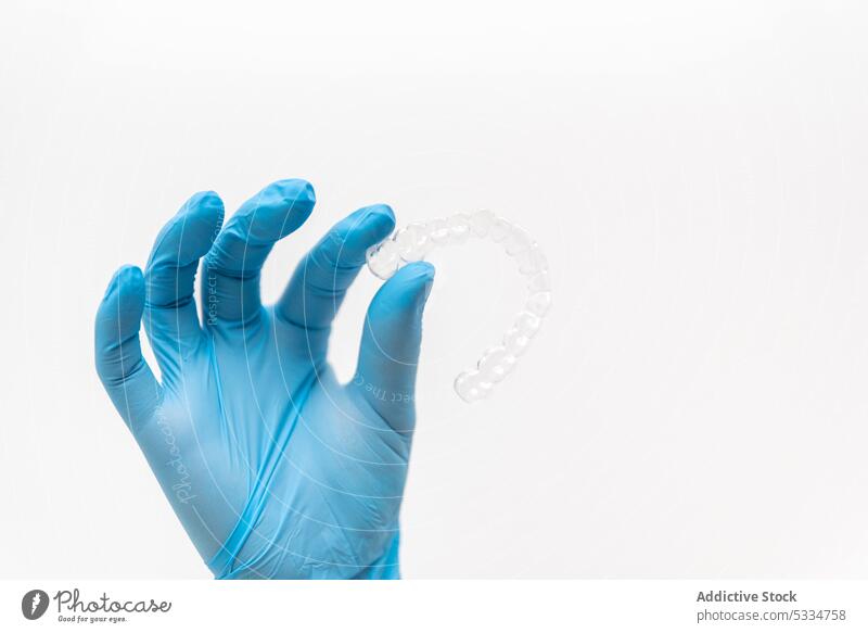 Hand mit Handschuhen, die eine transparente Klammer hält Zahnarzt übersichtlich Aligner unsichtbar dental Zahnmedizin Sauberkeit Arzt medizinisch Hygiene