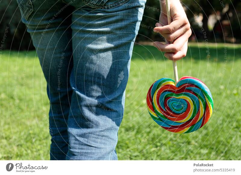 #A0# Lutscher lecker ungesund Frau draußen Zucker Ernährung süß Süßwaren Lebensmittel Essen Hand Snack Farbfoto Lollipop Nahaufnahme Jeanshose jeans
