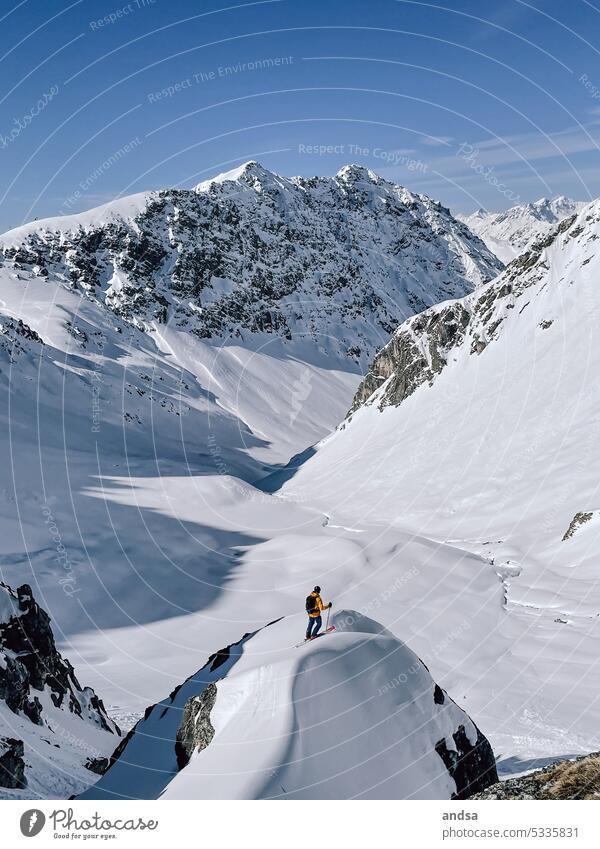 Skifahrer steht auf einem Felsen in den Alpen und schaut auf die Bergwelt Tourenskier Skier gebirgig Berge u. Gebirge massiv Schnee Winter Ausblick