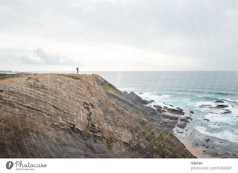 Der Reiseliebhaber genießt seine Freiheit in der portugiesischen Landschaft an der Atlantikküste und beobachtet das endlose Meer und die Formen der Klippen. Wandern auf dem Fischerpfad