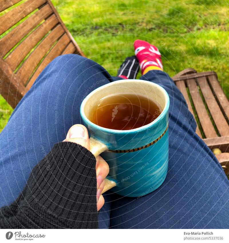 Teetasse in der Hand während der Auszeit im Garten mit hochgelegten Füßen Erholung Heißgetränk wärmend gemütlich Frau Tasse Finger Junge Frau Getränk