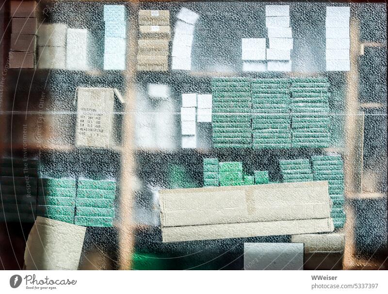 Hinter dem Fenster sieht man Stapel von Schachteln und Heften in gedeckten Farben Glas Regal gestapelt Schreibwaren Papier Pappe Kartons Vorrat Verkauf Lager