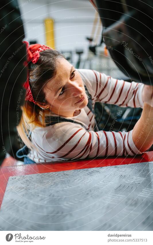 Mechanikerin überprüft Motorrad in der Fabrik Frau arbeiten überblicken Überprüfung Reparatur Porträt Garage Werkstatt Arbeitsplatz konzentriert professionell