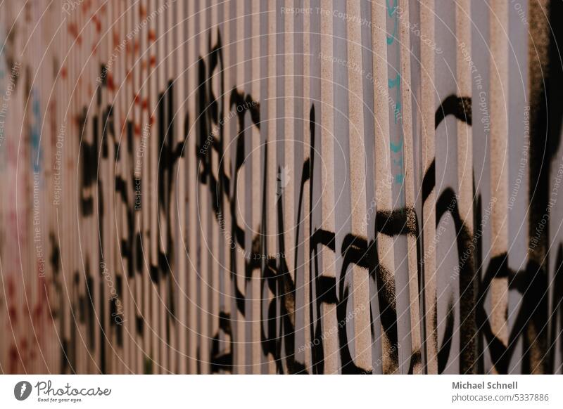 Graffiti an einer gewellten Wand Schriftzeichen Außenaufnahme Schmiererei Straßenkunst Fassade trashig Text unlesbar Jugendkultur vollgeschrieben