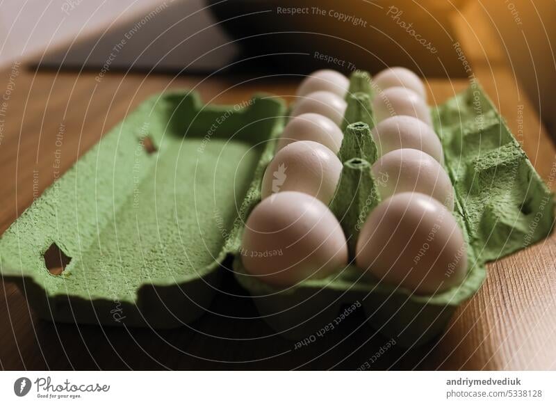Dutzend weiße frische Hühnereier in der grünen Karton-Ei-Tray auf Holztisch Hintergrund. Frische Bio-Eier in offenen Kartonpackung oder Eierbehälter. Nahrhaftes Essen. Farm's Produkte Konzept