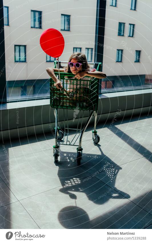 Mädchen in einem Einkaufswagen mit einem Luftballon hintergrundbeleuchtet Silhouette Unschuld Wunder Kindheit Abenteuer Hoffnung Freude Vorstellungskraft
