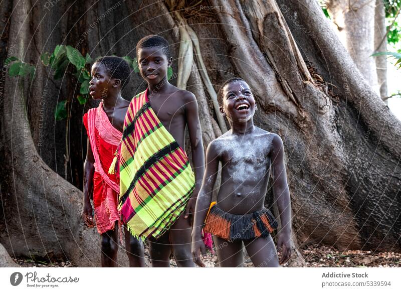 Positive Stammeskinder stehen in der Nähe eines großen Baumes Kinder Junge Wald Glück Natur lokal Tradition Afrikanisch einheimisch tropisch Kultur Umwelt