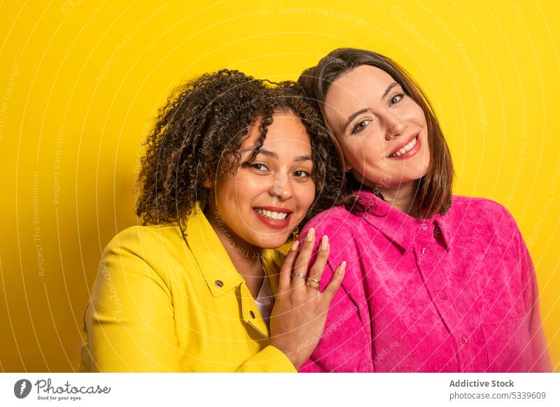 Fröhliche multiethnische Freunde schauen in die Kamera vor gelbem Hintergrund Frauen Freundin Lächeln Glück Zusammensein heiter Freundschaft positiv