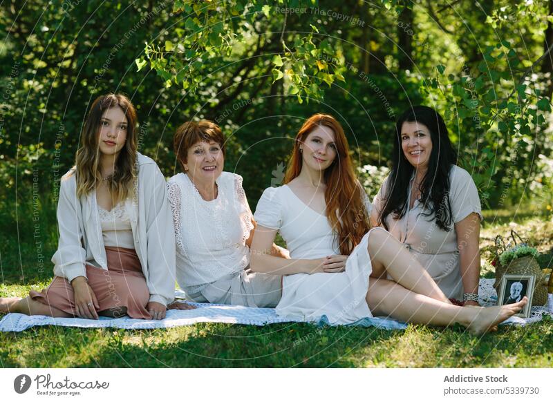 Fröhliche Frauen ruhen sich auf einer Decke im Park aus Sommer Picknick Rahmen Lächeln Foto Zusammensein Glück heiter Großmutter Tochter Enkelin positiv