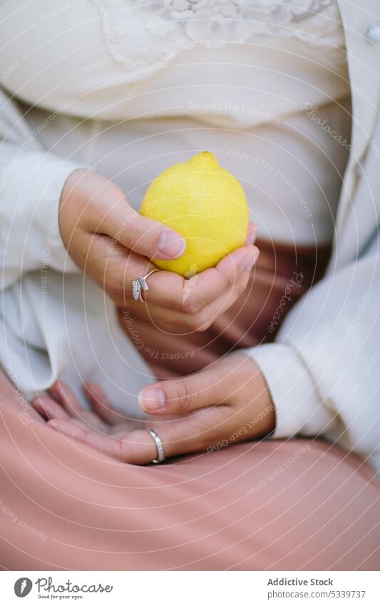 Crop-Frau mit reifer Zitrone in der Hand Accessoire Hemd Ring Frucht Stil Silber Seide Vitamin gelb frisch Zitrusfrüchte organisch natürlich sanft Angebot Stoff