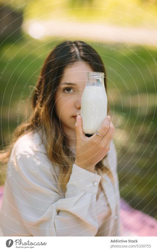 Verträumte Frau trinkt Milch aus einer Glasflasche Picknick Halt trinken Flasche melken Natur Getränk genießen frisch jung natürlich ruhig lange Haare sanft