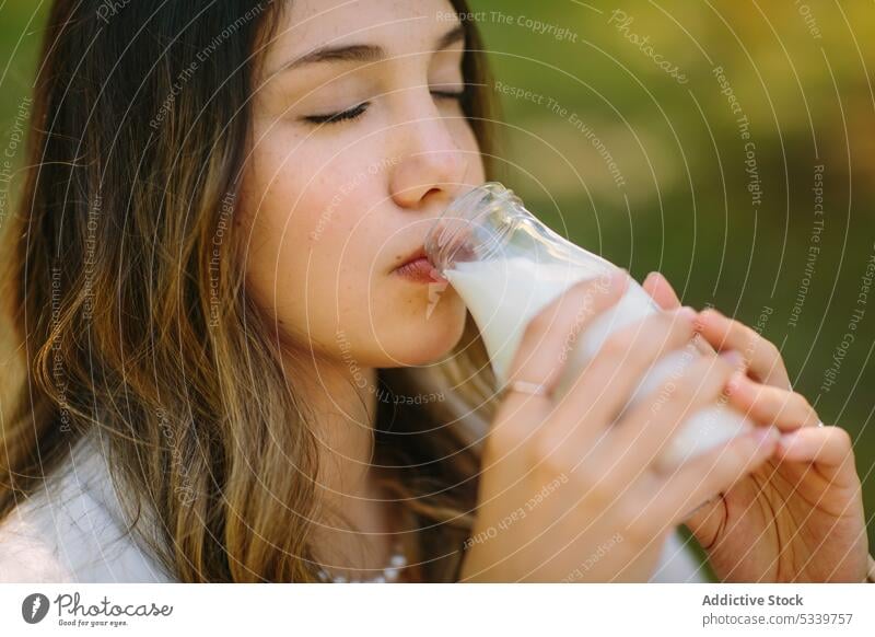 Verträumte Frau trinkt Milch aus einer Glasflasche Picknick trinken Flasche melken Augen geschlossen Natur Getränk genießen frisch jung natürlich ruhig