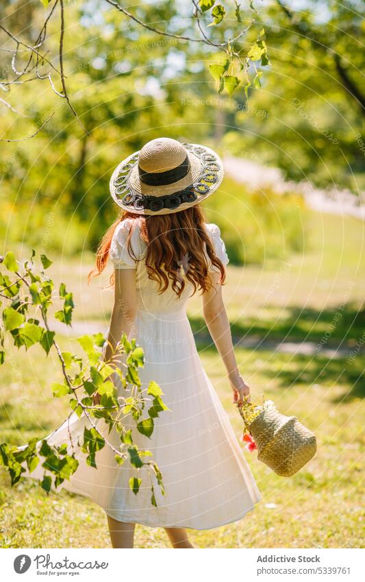 Unbekannte Frau mit Weidenkorb spaziert in sonniger Natur Spaziergang Korb Rasen Feld Sommer Landschaft Baum Garten Strohhut üppig (Wuchs) grasbewachsen Wiese