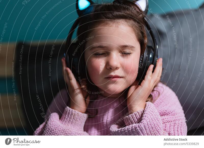 Ruhiges Kind mit Kopfhörern auf dem Bett sitzend Musik zuhören bezaubernd nachdenklich Schlafzimmer Apparatur wenig heimwärts Gerät Komfort zu Hause Windstille