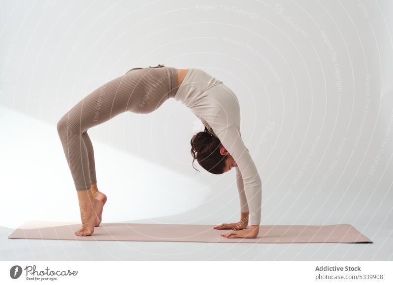 Weibliche Athletin übt die Radstellung beim Yoga Frau Wellness üben Achtsamkeit Training Gleichgewicht chakrasana Dehnung Wohlbefinden beweglich Atelier