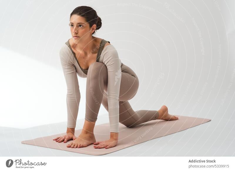 Gelassene Frau in Eidechsenhaltung auf der Yogamatte Dehnung Sportbekleidung üben Eidechsen-Pose Asana Gesunder Lebensstil uttana pristhasana beweglich Fokus