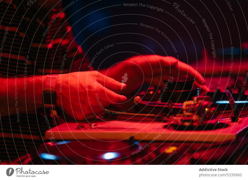Crop-DJ legt Platte in rotem Neon auf Mann dj Party Musik Konsole Nacht mischen Gerät unterhalten spielen Audio professionell Plattenteller benutzend ausführen
