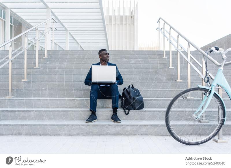 Schwarzer Geschäftsmann arbeitet auf der Straße an einem Laptop Unternehmer Arbeit abgelegen Tippen benutzend freiberuflich Job online Internet Mann Fahrrad