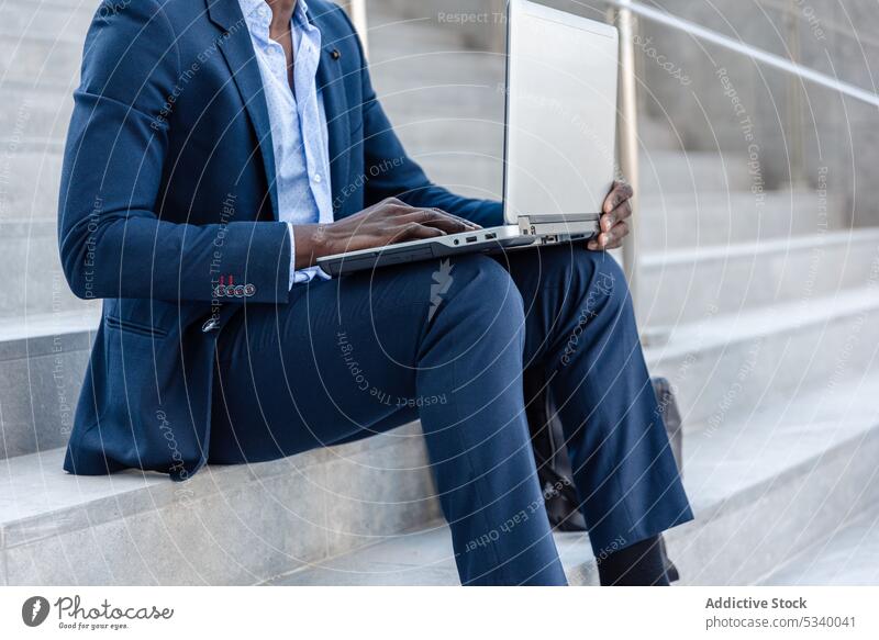 Anonymer schwarzer Geschäftsmann arbeitet auf der Straße an einem Laptop Unternehmer Arbeit abgelegen Tippen benutzend freiberuflich Job online Internet Mann
