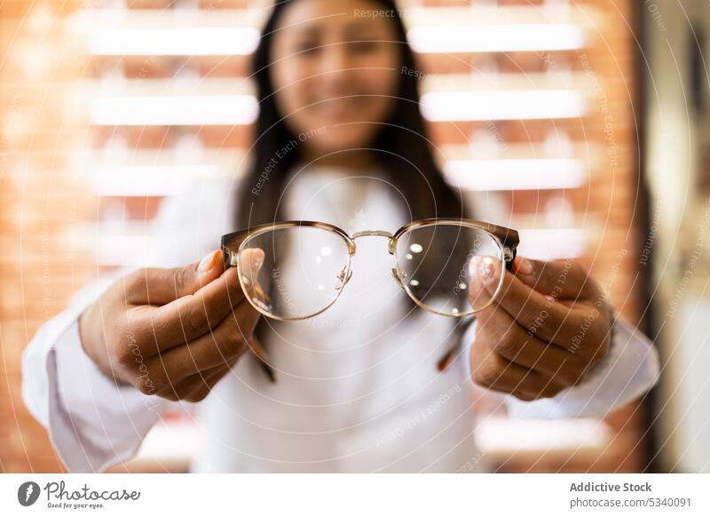 Positiv eingestellte Ärztin mit Brille Frau Lächeln zeigen Arbeit heiter Glück optisch Ophthalmologe manifestieren professionell Job jung lange Haare positiv