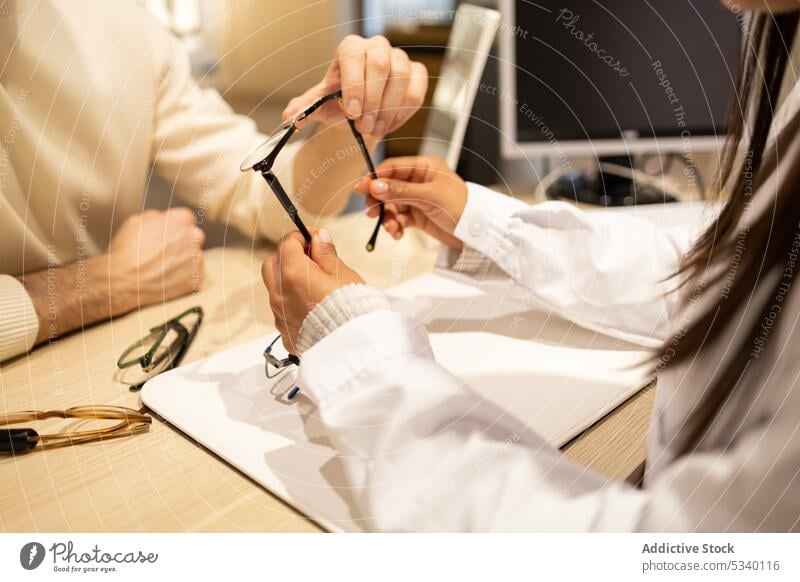 Anonymer Mann im Gespräch mit Augenarzt über Brillen im Geschäft Kunde Ophthalmologie Klient optisch wählen Ophthalmologe konsultieren kaufen Laden Wahl Frau