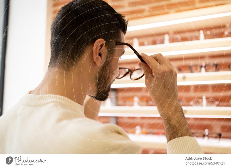 Anonymer Mann wählt in einem Geschäft eine Brille aus wählen optisch Laden Kunde Wahl Klient männlich Augenlicht Sale Vollbart Sehvermögen Werkstatt Käufer