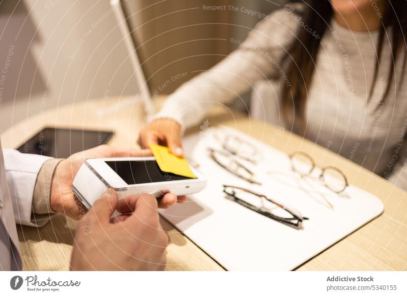 Crop-Frau bei der Bezahlung einer neuen Brille Kreditkarte bezahlen berührungslos Kauf Transaktion Kunde benutzend optisch Laden Drahtlos Zahlung Werkstatt