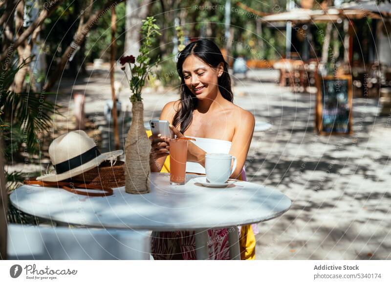 Konzentrierte Frau, die in einem Straßencafé auf ihrem Smartphone surft Café Getränk Tasse Heißgetränk Telefon Konzentration trinken Nachricht Tulum Mexiko