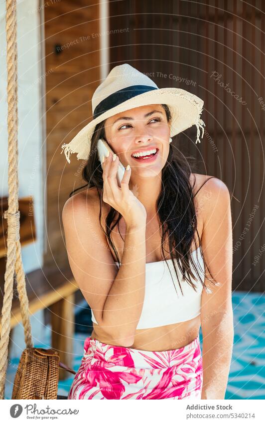Fröhliche Frau spricht auf einer Schaukel mit ihrem Smartphone reden Resort Lächeln Sommer Gespräch Glück Telefon tropisch Tulum Mexiko mexikanisch asiatisch