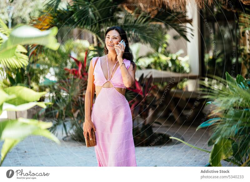 Glückliche Frau spricht mit Smartphone auf der Straße mit Palmen Garten Lächeln reden Handfläche tropisch Sommer sprechen Telefonanruf mexikanisch Mexiko