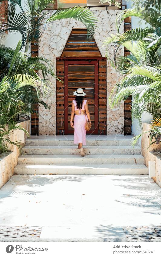Rückenansicht Frau geht die Treppe hinunter im tropischen Park Tourist Resort Garten Gebäude Urlaub nachdenklich Sommer Stil reisen Spaziergang mexikanisch