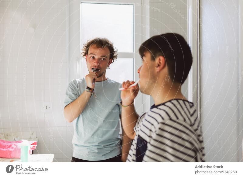 Ruhige schwule Männer beim Zähneputzen im Badezimmer Paar Bürste Morgen Routine Hygiene Reflexion & Spiegelung heimwärts Zusammensein Zahnbürste Sauberkeit jung