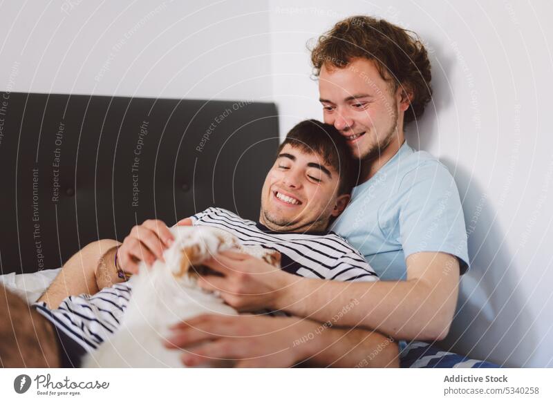 Fröhliches schwules Paar, das sich auf dem Bett umarmt Männer kuscheln sich[Akk] entspannen Wochenende Zusammensein heimwärts Glück Liebe ruhen Lügen jung