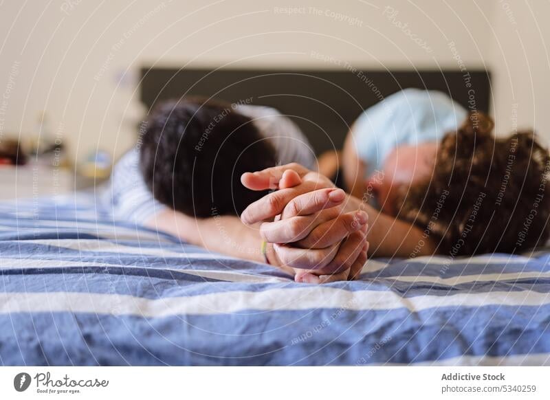 Unerkennbares schwules Paar hält sich auf dem Bett an den Händen Männer Händchenhalten sich[Akk] entspannen Liebe heimwärts Partnerschaft romantisch