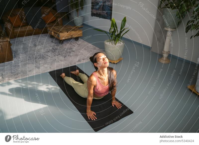 Schlanke Frau übt Cobra-Pose im Studio Yoga Asana Kobra-Pose Augen geschlossen Achtsamkeit üben beweglich Zen Atelier Windstille bhujangasana Barfuß Stressabbau