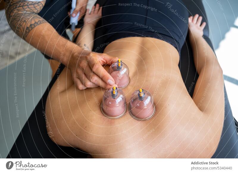 Männlicher Therapeut behandelt den Rücken einer Kundin mit Schröpfmassage Masseur Massage Frau Vakuum Rehabilitation Therapie Spezialist Hijama