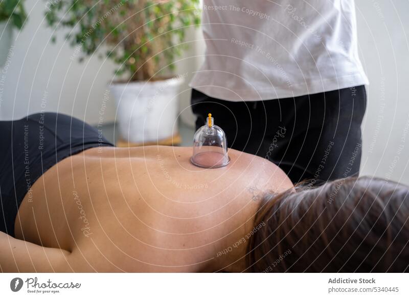 Männlicher Therapeut behandelt den Rücken einer Kundin mit Schröpfmassage Masseur Massage Frau Vakuum Rehabilitation Therapie Spezialist Hijama