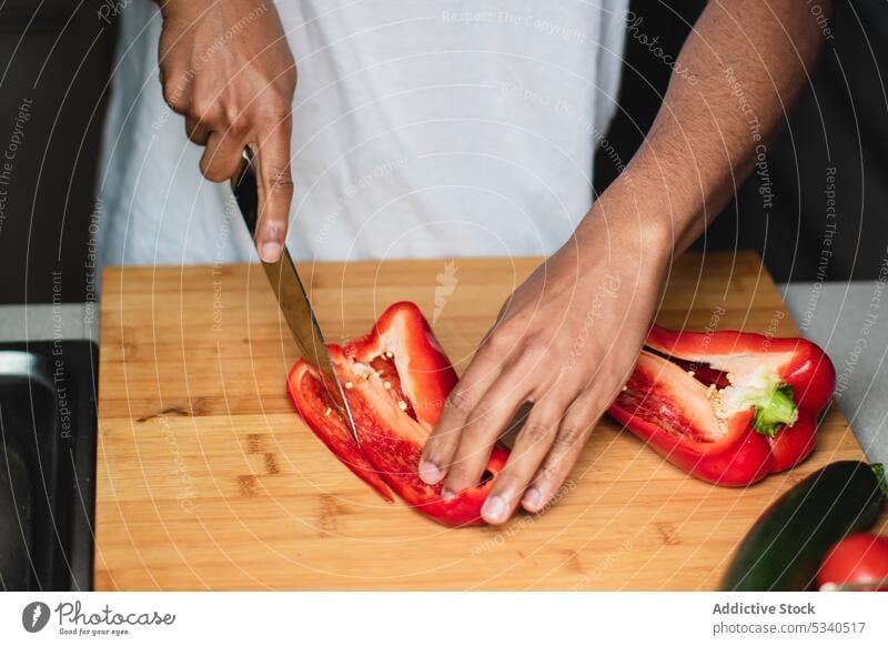 Anonymer Mann, der eine Paprika auf einem Schneidebrett schneidet Salatbeilage geschnitten Messer vorbereiten Gemüse Küche Koch Gesundheit Lebensmittel