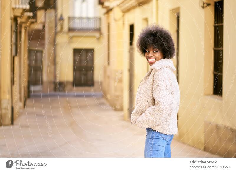 Glückliche ethnische junge Frau mit Afrofrisur Lächeln Afro-Look Porträt positiv heiter froh lange Haare gemütlich Optimist Vorschein Dame Zahnfarbenes Lächeln