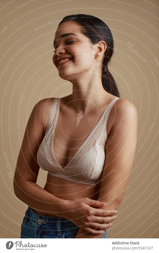 Fröhliche Frau in Unterwäsche lächelt mit geschlossenen Augen Lächeln Glück Augen geschlossen positiv BH Porträt heiter Stil Jeanshose jung Freude Model