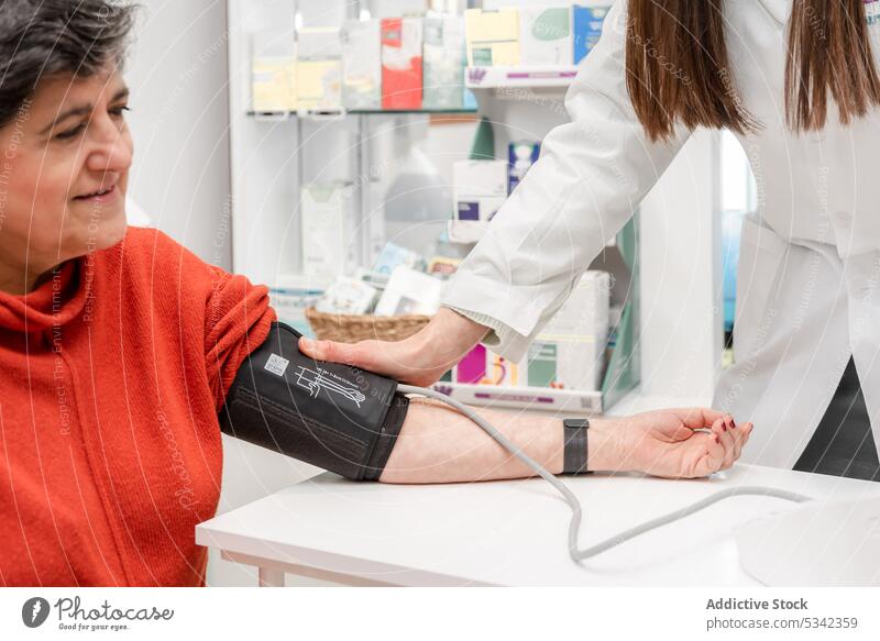 Frau in medizinischer Uniform misst den Blutdruck eines Patienten Frauen Apotheker messen Drogerie Lächeln Medizin positiv Leckerbissen Sphygmomanometer