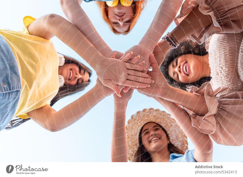 Fröhliche, vielfältige Freunde, die ihre Hände zusammenlegen Menschengruppe Frauen Hände stapeln Zusammensein Lächeln Freundschaft Glück heiter Einheit Sommer