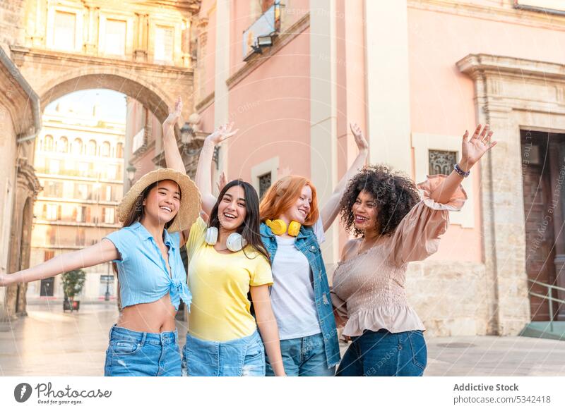 Glückliche, bunt gemischte Freunde stehen mit erhobenen Händen auf der Straße Menschengruppe Freundin feiern Gebäude Großstadt Frauen Freundschaft