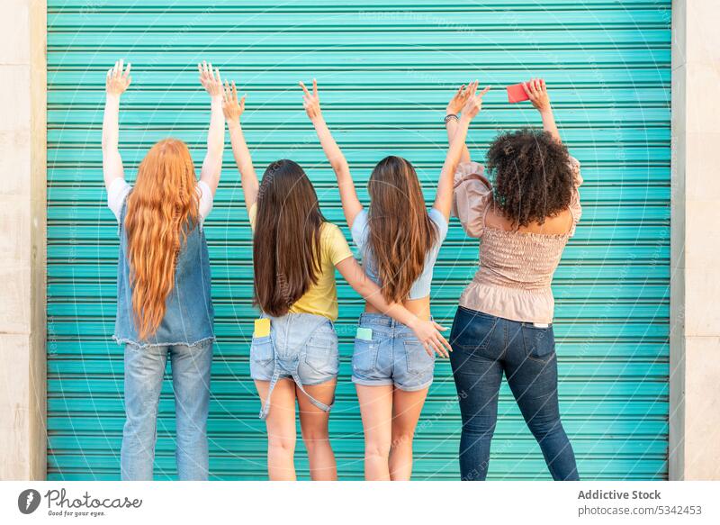 Gruppe verschiedener Frauen mit erhobenen Händen gegen eine grüne Tür Freundschaft Zusammensein Freundin Straße Menschengruppe Glück Partnerschaft Freude