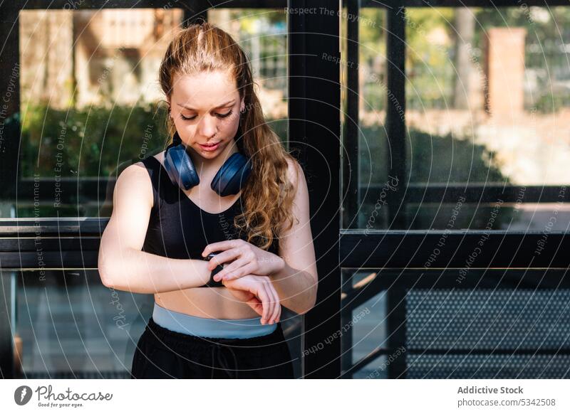 Frau überwacht Laufleistung auf Smartwatch intelligente Uhr zuhören Kopfhörer Musik Headset Sportbekleidung berühren Läufer passen jung Drahtlos prüfen Tracker