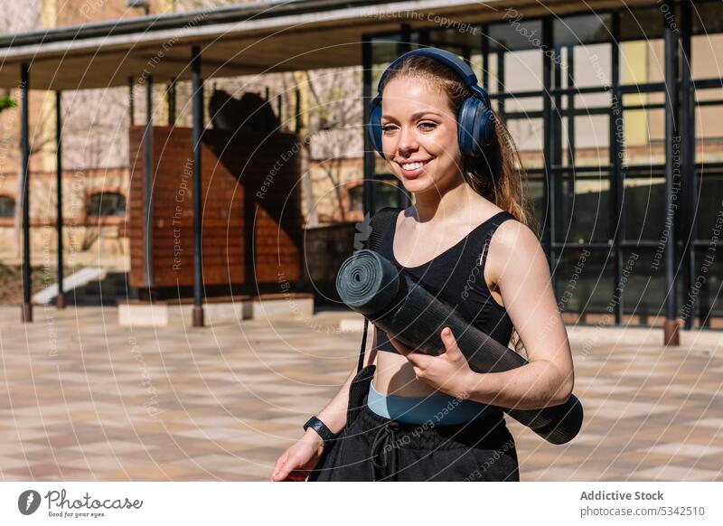 Fröhliche Frau, die auf der Straße mit Kopfhörern Musik hört Training zuhören Unterlage Headset Fitness Lächeln Sport Drahtlos passen jung Gerät Wellness