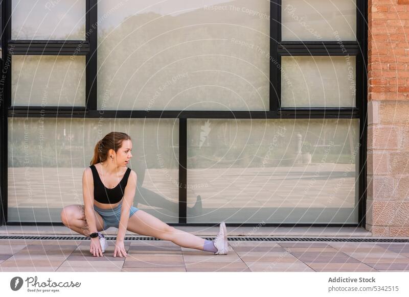 Schlanke Frau macht Yoga Seite Ausfallschritt Übung skandasana Seitenlonge Dehnung üben Training beweglich Straße Sportbekleidung Wellness Energie Wohlbefinden