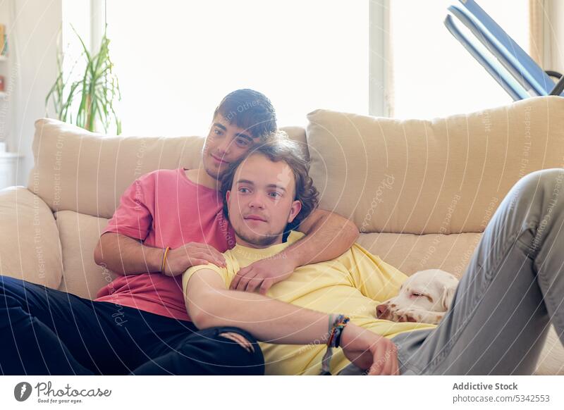 Homosexuelles Paar umarmt sehr intim auf der Couch schwul Männer Hund Sofa Umarmung Zusammensein ruhen Transgender Homosexualität männlich heimwärts Haustier